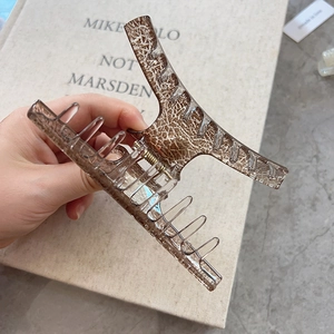 Detailed view of a large brown resin hair claw clip with a strong metal spring and ice texture