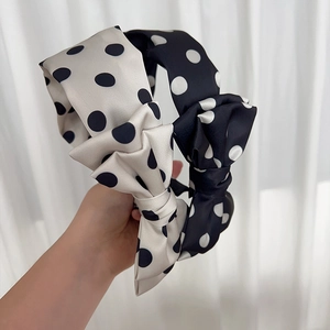 Elegant polka dot bow headband in black and white satin finish for hair styling