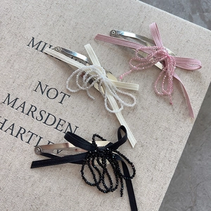 Close-up of pink, white and black beaded bow hair clips on a textured background