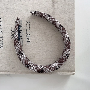 Detail of a brown plaid headband with small bow embroidery and a handmade label