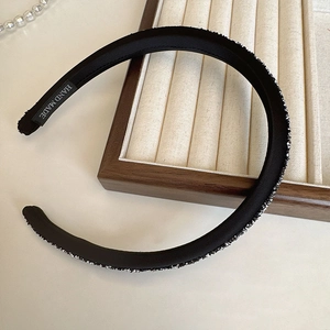Sparkling black sponge headband with rhinestones and handmade label in a 45-degree view