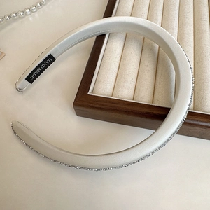 Elegant cream satin headband with sparkling rhinestones and handmade label on display