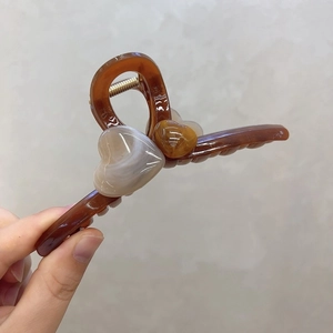 Détail de la grande pince à cheveux ambre avec des accents de cœur à texture marbrée