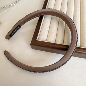 Detailed view of dark brown sponge headband with rhinestone trim and Hand Made label