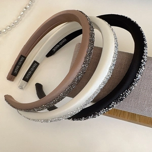 Close-up of three sparkling padded headbands with rhinestones and handmade woven labels