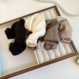 Assorted satin silk scrunchies with elegant pearl accents in a wooden jewelry box display