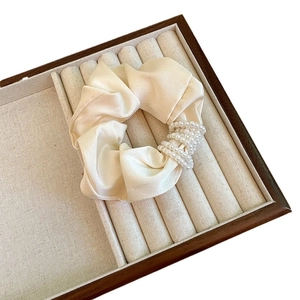 Elegant cream satin scrunchie featuring five rows of wrap-around pearls on a wooden display