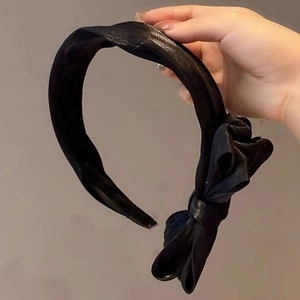 Détail d'un serre-tête en satin noir avec un nœud latéral élégant pour un look chic