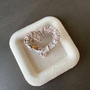Détail de la pince à cheveux cœur en tweed rose avec un badge métallique doré LOVE