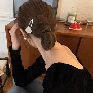 Elegant white camellia hair clip worn on a low bun hairstyle for women in a vintage setting