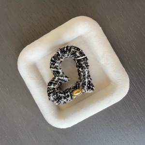 Détail de la pince à cheveux en tweed en forme de cœur avec boucle en métal dorée