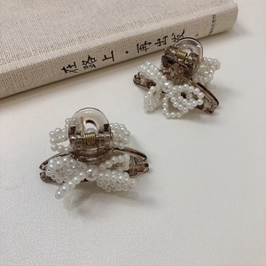 Detail of amber acrylic hair clips with faux pearls arranged in a bow shape on a book