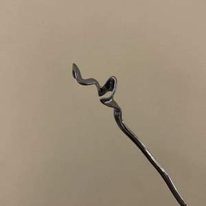 Détail d'un pic à cheveux métallique ondulé noir fusil pour chignons élégants