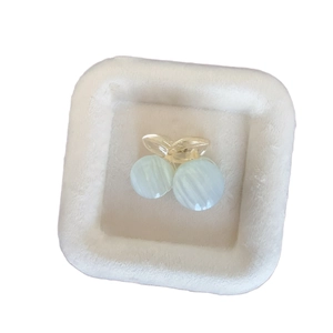 Blue striped cherry hair claw clip with pearl cat eye stones on a white velvet display tray
