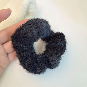 Gros plan sur le chouchou noir en peluche montrant la texture douce de la fausse fourrure