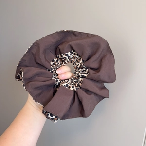Oversized brown and leopard print double-layered scrunchie held by hand for hair styling