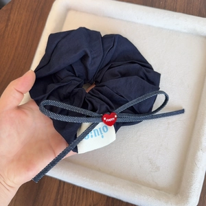 Detail showing navy blue pleated scrunchie with denim bow and red Happy heart charm