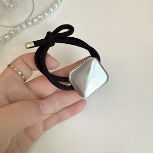 Close-up of black elastic hair tie with square brushed silver metal and gold finish tips