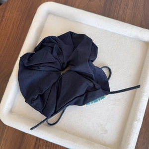 Dark blue denim hair scrunchie with bow and drawstring on white tray
