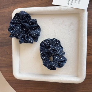 Gros plan de deux chouchous bleu marine à pois blancs avec bordure en dentelle sur plateau