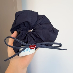 Close-up of navy blue pleated scrunchie with a red heart Happy charm and bow detail