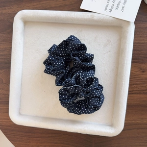 Chouchou élégant bleu marine à pois blancs avec bordure en dentelle sur plateau velours