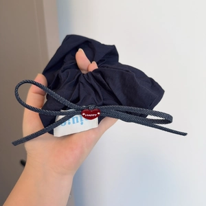 Close-up of navy blue scrunchie with denim bow and red heart charm reading Happy