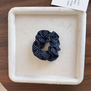 Chouchou élégant bleu marine à pois avec dentelle sur un plateau de présentation beige