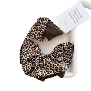 Brown leopard print scrunchie and bow hair clip set on a white plush velvet tray