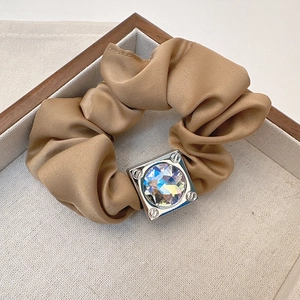 Detail of champagne satin scrunchie with a square silver buckle and faceted gemstone