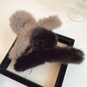 Détail de pinces à cheveux en peluche noire et kaki sur un plateau minimaliste