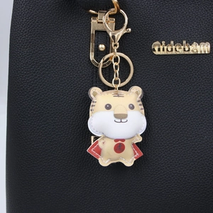 Porte-clés tigre en cuir jaune avec cape rouge sur un sac à main en cuir noir