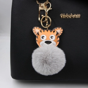 Porte-clés tigre en cuir avec pompon en fausse fourrure grise sur un sac à main noir