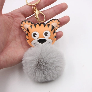 Détail du porte-clés tigre en peluche avec pompon gris et fermoir en métal doré