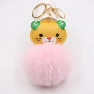 Detail of cartoon tiger keychain featuring a large fluffy pink pompom and gold metal ring