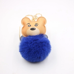Detail of cute tiger plush keychain featuring a dark blue fur ball and brown leather stitching