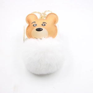 Close-up of brown leather bear head and fluffy white faux fur pompom with golden keychain