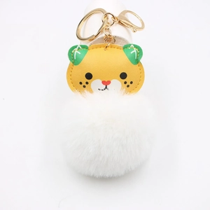 Close-up of cute cartoon tiger plush keychain with white pom-pom and gold metal clasp