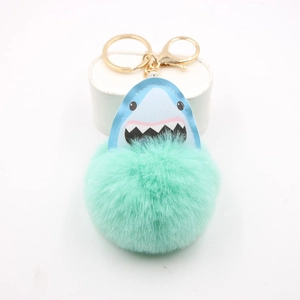 Detail of shark plush ball keychain with golden metal ring and light blue leather shark head
