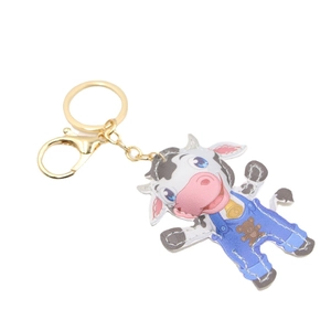 Mignon porte-clés vache en cuir avec salopette bleue et breloque cloche dorée sur fond blanc