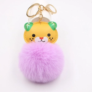 Detail of yellow cat charm with purple faux fur pompom and golden metal keychain clip