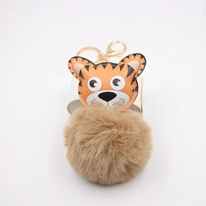 Détail d'un porte-clés tigre en cuir avec pompon marron en fausse fourrure et crochet doré