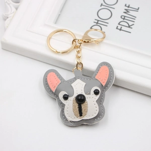 Close-up of grey and white leather bulldog keychain with golden lobster clasp and stitching