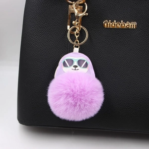 Purple faux fur sloth charm keychain with gold metal buckle on a black leather handbag