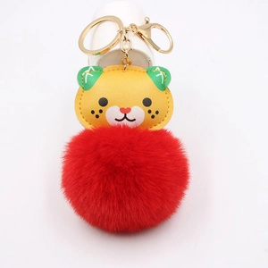 Detail of cartoon tiger leather charm with large red faux fur pompom and gold keychain