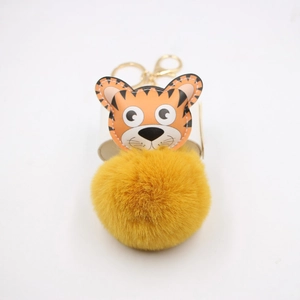 Détail du pendentif tigre en cuir avec pompon en fourrure jaune et fermoir doré en métal