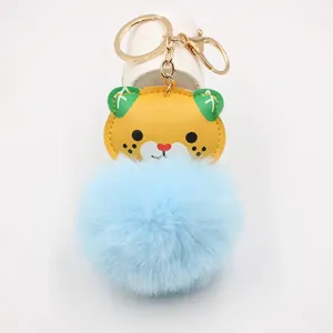 Detailed view of yellow leopard PU head and oversized light blue faux fur ball keychain