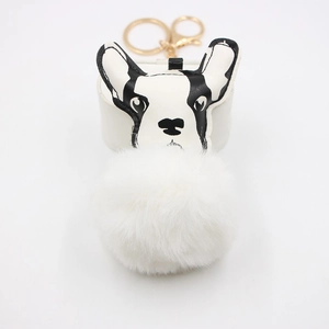 Détail d'un pompon en fausse fourrure et d'un charm bouledogue français noir et blanc sur porte-clé