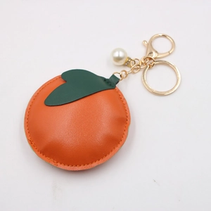 Close-up of leather persimmon keychain with golden hardware and pearl detail
