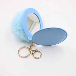 Light blue faux fur pompom keychain with an integrated mini makeup mirror on gold chain